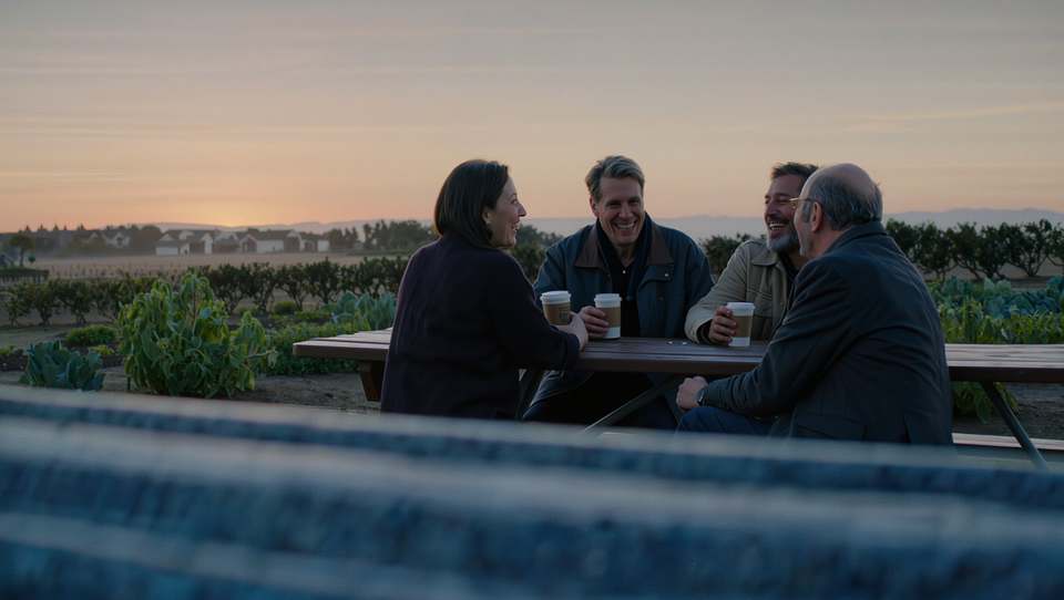 Friends talking at a picnic table in the early morning